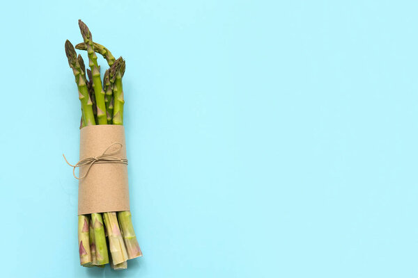 Кучка свежей зеленой спаржи на синем фоне