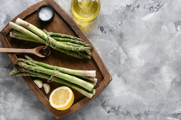 Taze yeşil kuşkonmaz, sarımsak ve limon dolu ahşap tahta tahta.