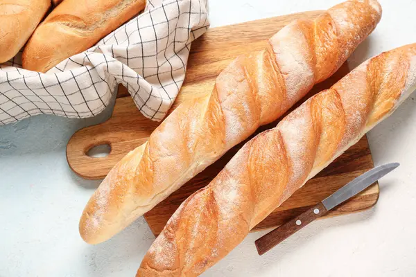 Açık mavi arka planda taze baget ekmeği olan ahşap tahta.