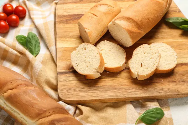 Açık mavi arkaplanda taze baget, fesleğen ve kiraz domatesli ahşap tahta, yakın plan.