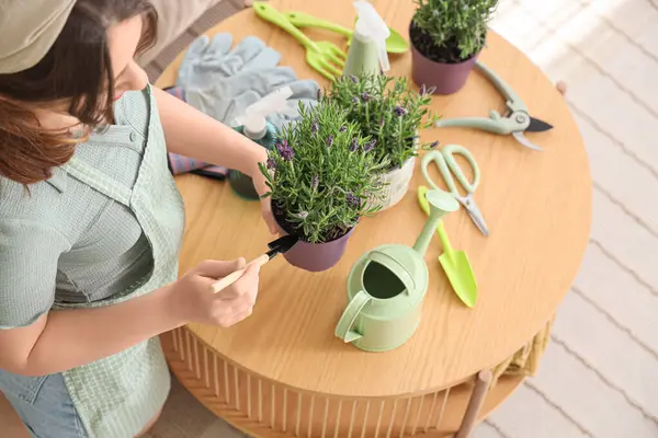 Evinde kürek ve lavanta çiçekleri olan genç bir kadın.