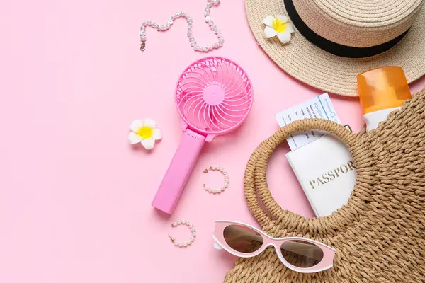 Kadın yaz aksesuarları, pasaport, bilet ve pembe arka planda kısa mesaj için yeri olan mini vantilatör.