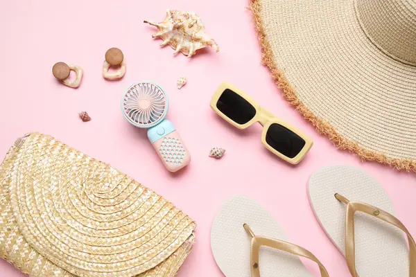 Kadın aksesuarları ve pembe arka planda mini fanı olan bir çanta.