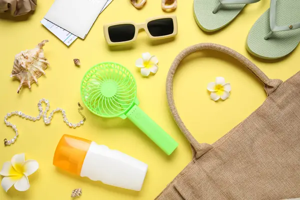 Kadın yaz aksesuarları ve sarı arka planda mini yelpaze.