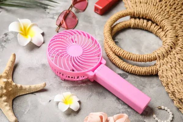 Yaz aksesuarları ve arka planda mini fan olan bir çanta.