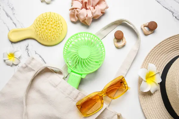 Kadın yaz aksesuarları ve arka planda mini fanı olan bir çanta.