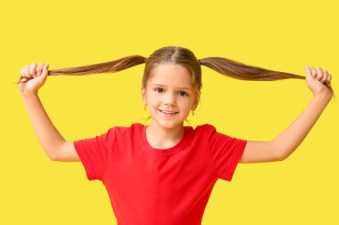 Sarı arka planda örgülü mutlu küçük kız.