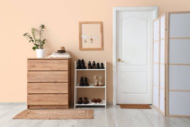 Çekmece, kapı, ayakkabı standı ve bej duvarda anahtar olan şık bir salon.