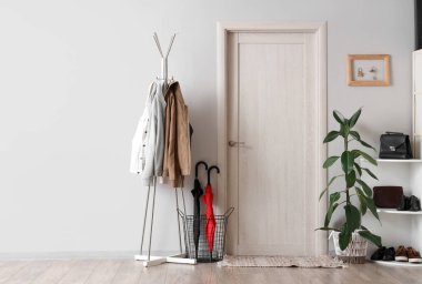 Elbise askısı, kapı, ayakkabı standı ve beyaz duvarda anahtar tutacağı olan şık bir salon.