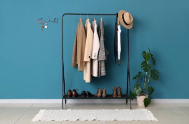 Mavi duvarında elbise askılığı, saksı ve anahtar tutacağı olan şık bir salonun içinde.