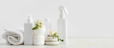 Farklı kozmetik ürünleri seti, temiz havlu, spa taşları ve açık arkaplanda çiçekler