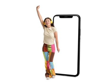 Beyaz arka planda kulaklığı ve büyük akıllı telefonu olan genç Asyalı kadın.