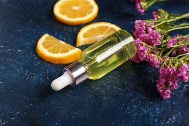 Güzel çiçekli bir şişe kozmetik yağı ve mavi arka planda limon.
