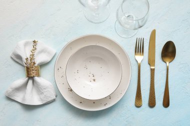 Altın çatal bıçak ve açık mavi masa peçetesiyle şık bir masa.