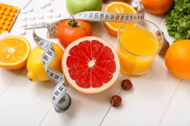 Farklı sağlıklı ürünlere, haplara ve beyaz ahşap arka planda ölçüm bandına sahip kompozisyon, yakın plan