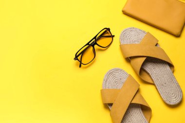 Çantalı ve güneş gözlüklü sarı sandaletler.