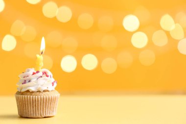 Sarı masanın üzerinde yanan mumla bulanık ışıklara karşı nefis bir doğum günü pastası.