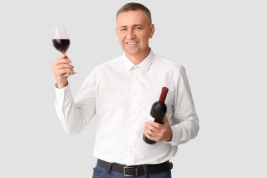 Beyaz arka planda cam ve şarap şişesi olan yakışıklı olgun bir adam.