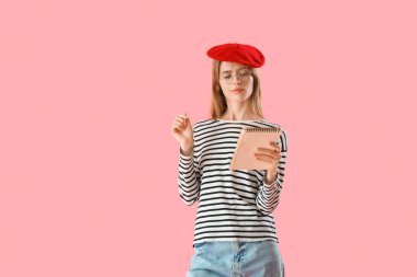 Pembe arka planda not defteri olan düşünceli bir kadın yazar.