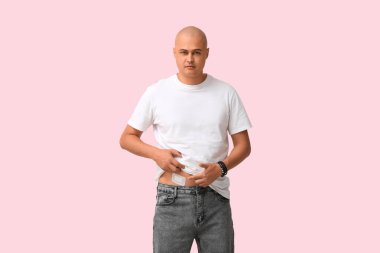 Pembe arka planda apandisit ameliyatı geçirmiş genç bir adam.