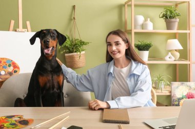 Sevimli Doberman köpeği ve evde çalışan güzel, mutlu bir kadın.