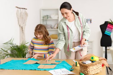 Atölyede kumaş kesen kadın terziler.