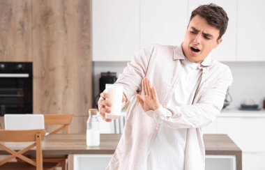 Genç adam mutfakta bir bardak sütü reddediyor.