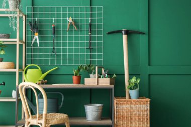 Tahtası, bahçe aletleri ve yeşil duvarın yanında bitkileri olan işyeri