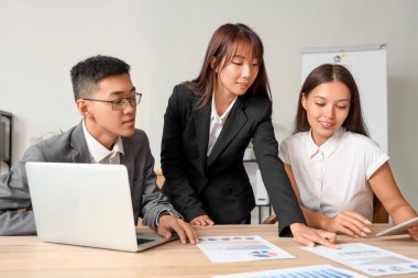 Ofisteki masada diyagramlarla çalışan Çinli işadamları