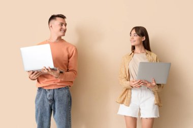 Bej arka planda dizüstü bilgisayar kullanan genç çift