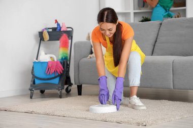 Robot elektrikli süpürgesi olan Asyalı kadın hademe.