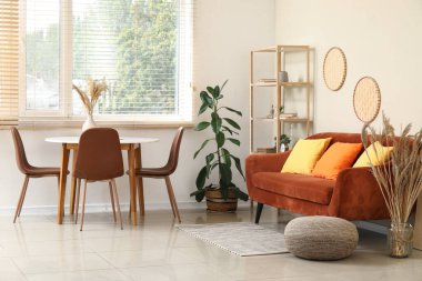 Oturma odasının iç tarafında yemek masası, kanepe ve çiçek var.