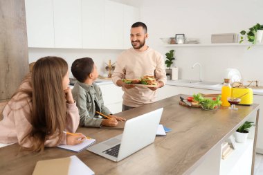 Babalarıyla evde ödev yapan sevimli çocuklar.