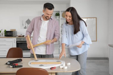 Mutfakta elle montaj masası olan mutlu hamile çift.