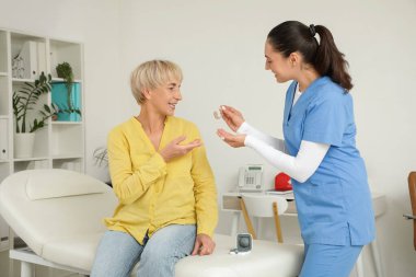 Doktor klinikte olgun kadınlara işitme cihazı veriyor.