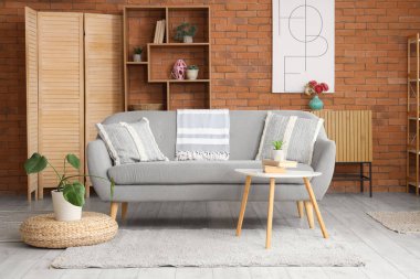 Rahat gri kanepesi, kahve masası ve çiçekli şık bir oturma odası.