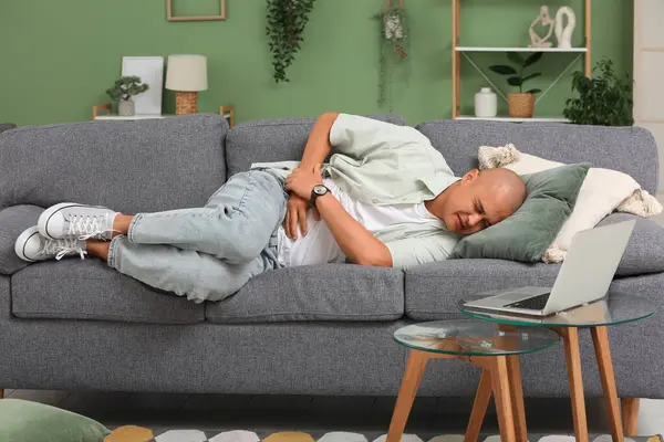 Apandisiti olan genç bir adam evdeki kanepede yatıyor.