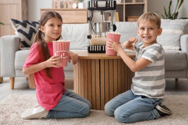 Evde patlamış mısır makinesi olan küçük çocuklar.