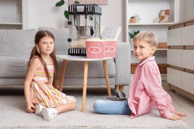 Evde patlamış mısır makinesi olan küçük çocuklar.