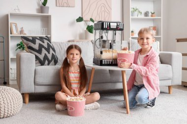 Evde patlamış mısır makinesi olan küçük çocuklar.