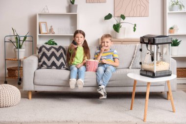 Patlamış mısırlı küçük çocuklar TV 'de film izliyorlar.