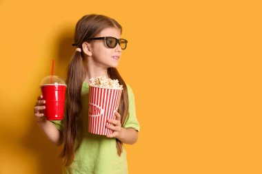 Sarı arka planda patlamış mısır ve soda bardaklı küçük kız.