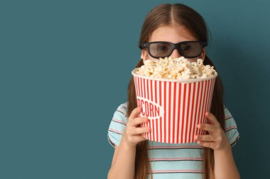 Mavi arka planda patlamış mısırlı üç boyutlu gözlüklü küçük kız, yakın plan.