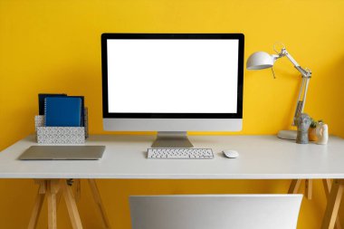 Ofiste sarı duvarın yanında lambalı boş bilgisayar monitörü.