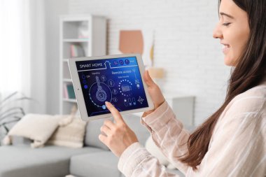 Genç bir kadın odasındaki akıllı ev güvenlik kontrol panelini kullanıyor.