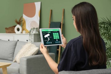 Akıllı ev güvenlik sistemi kontrol paneli olan genç bir kadın.