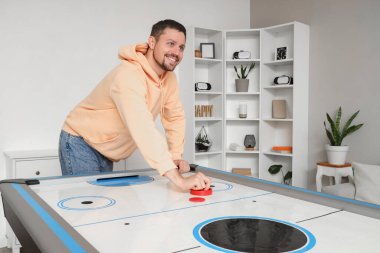 Genç adam evde hokey oynuyor.