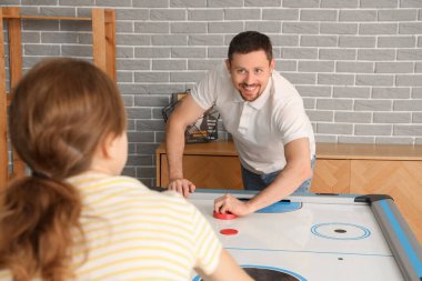 Genç adam ve arkadaşı evde hokey oynuyorlar.