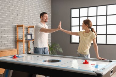 Genç arkadaşlar evlerinde hokey oynarken birbirlerine beşlik çakıyorlar.