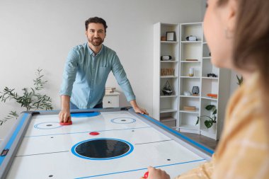 Genç adam ve kız arkadaşı evde hokey oynuyorlar.